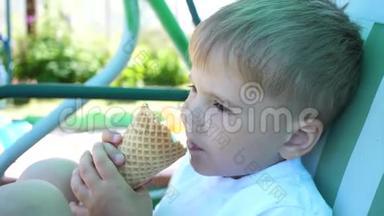 一个小男孩坐在公园的秋千上，高兴地吃冰淇淋。 炎炎夏日，冷甜甜点
